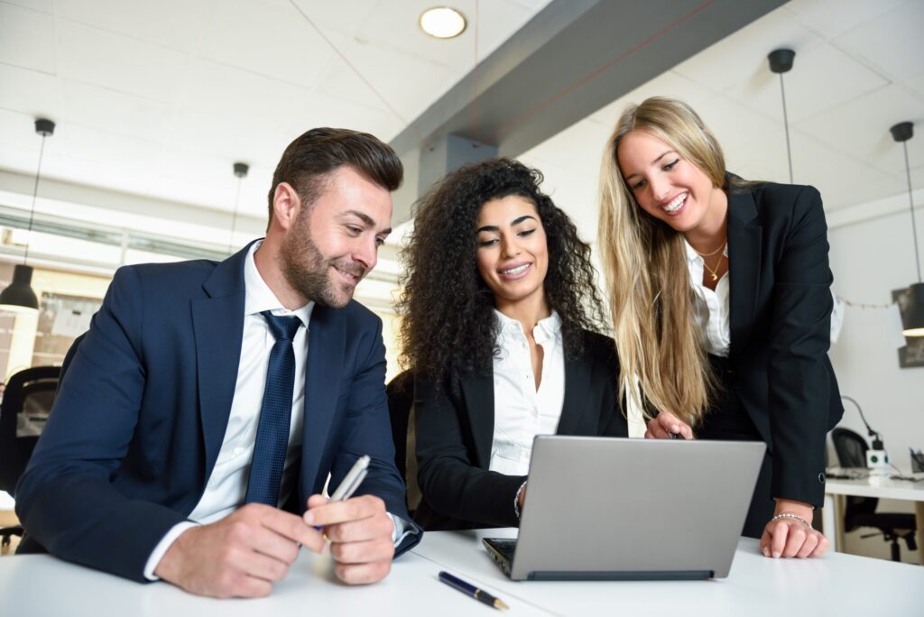 multi ethnic group of three businesspeople meeting in modern office two women and man wearing suit looking at laptop computer scaled.jpg